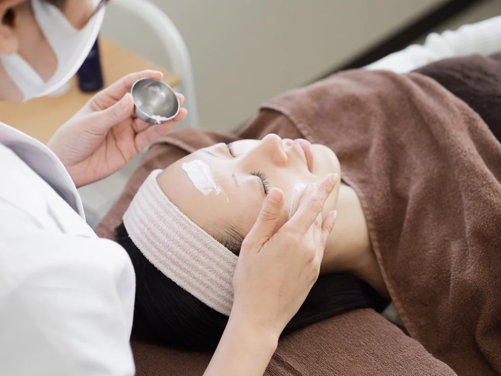 Japanese woman receiving professional facial skin care treatment at beauty clinic